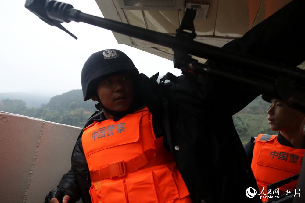 图9 艇首战位值勤的警察赶上阴雨冷风，战友送来御寒的棉衣。