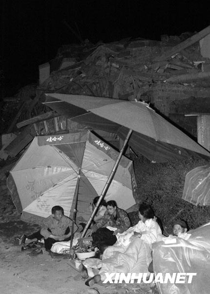 2008年5月13日凌晨，绵竹市汉旺镇的一些居民露宿在垮塌的建筑前。