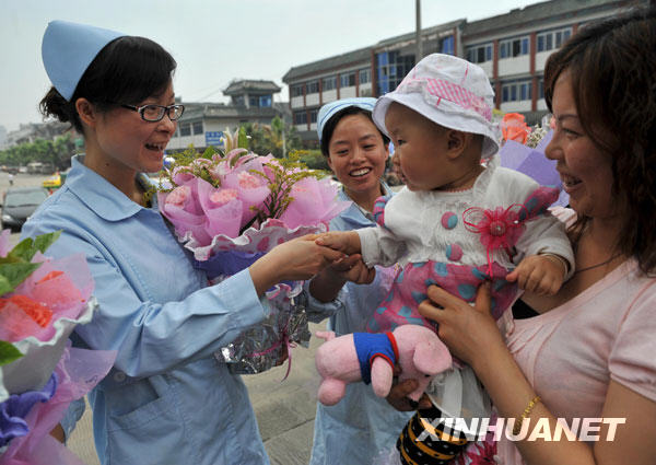 5月11日，“地震宝宝”代无极（左三）和护士王丽阿姨（左一）握手，她的妈妈（右一）今天特地为三位护士每人送上了一束鲜花。